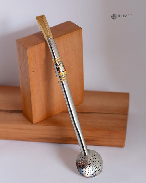 Bomba Ilumet com bocal dourado e detalhe decorativo, fotografada sobre madeira